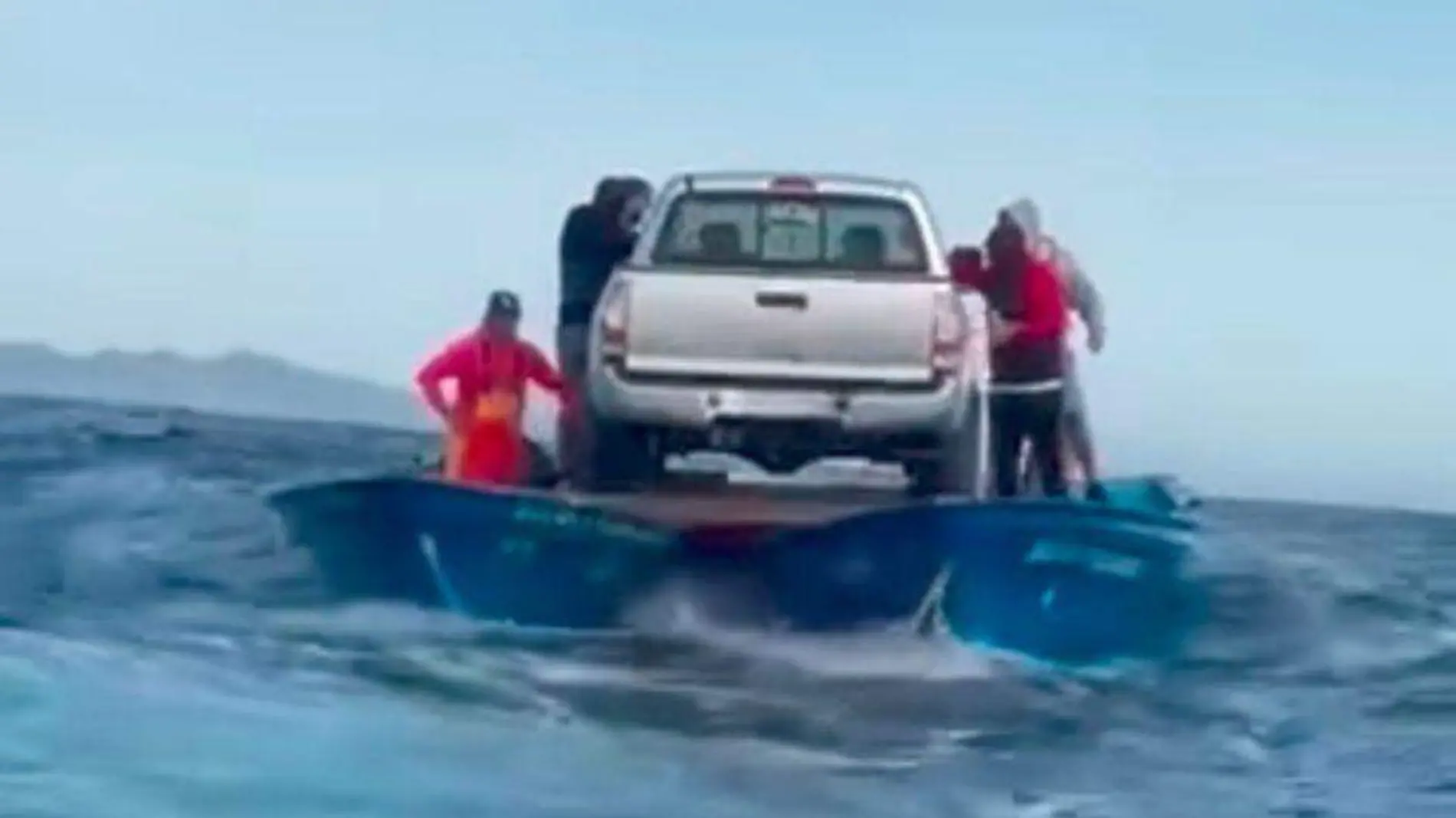 Transportan carro sobre lanchas en el mar